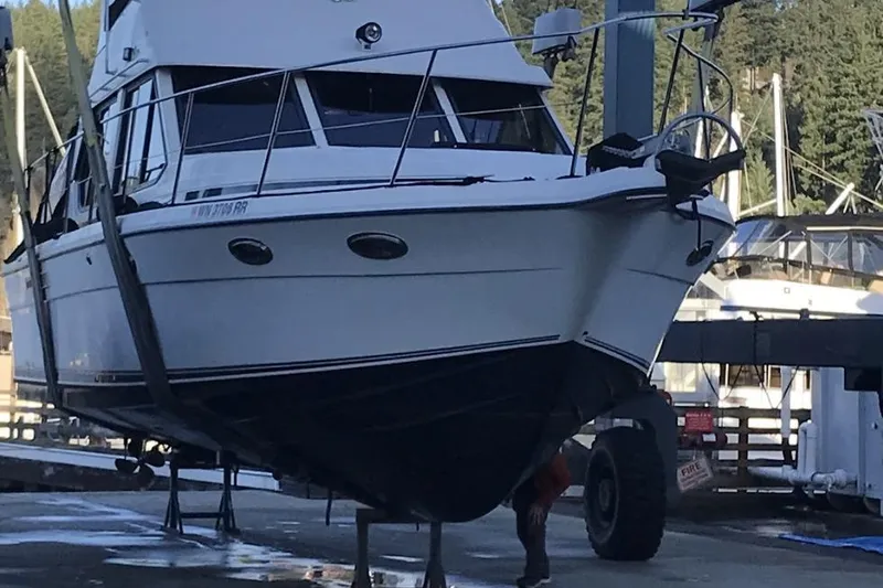 Slide: The Image of A boat is being lifted at a marina, surrounded by trees and other vessels. - 5