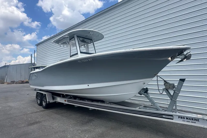 Slide: The Image of 2019 Sea Hunt Ultra 275 SE boat on trailer, parked beside a metal building. - 2