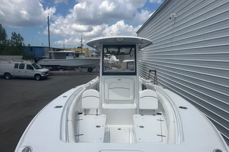 Slide: The Image of 2019 Sea Hunt Ultra 275 SE boat docked near a metal building under cloudy skies. - 3