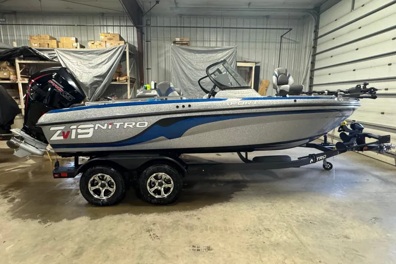 The Image of 2026 Nitro ZV19 Sport Pro boat in a garage, featuring sleek design and dual-axle trailer. - 0
