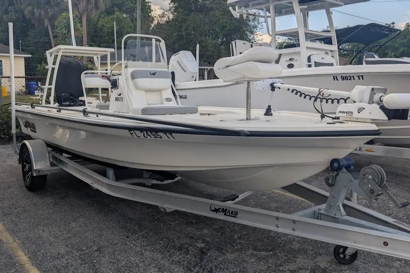 The Image of 2024 Mako 18 LTS boat on trailer, parked outdoors, featuring Minn Kota trolling motor. - 1