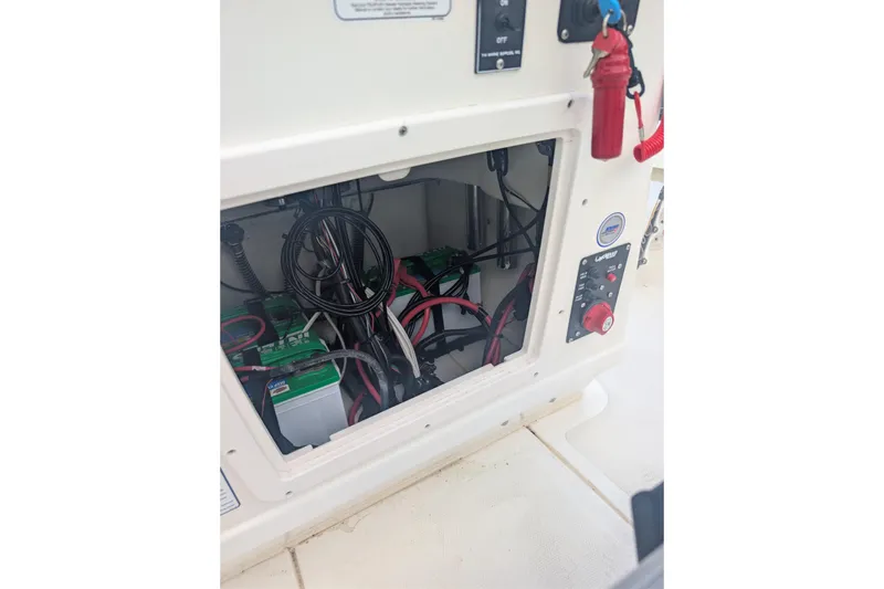 Slide: The Image of 2024 Mako 18 LTS boat electrical compartment with wiring and battery setup. - 10