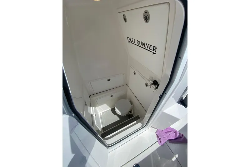 Slide: The Image of 2026 Reef Runner 280 boat interior with compact restroom and storage space. - 18