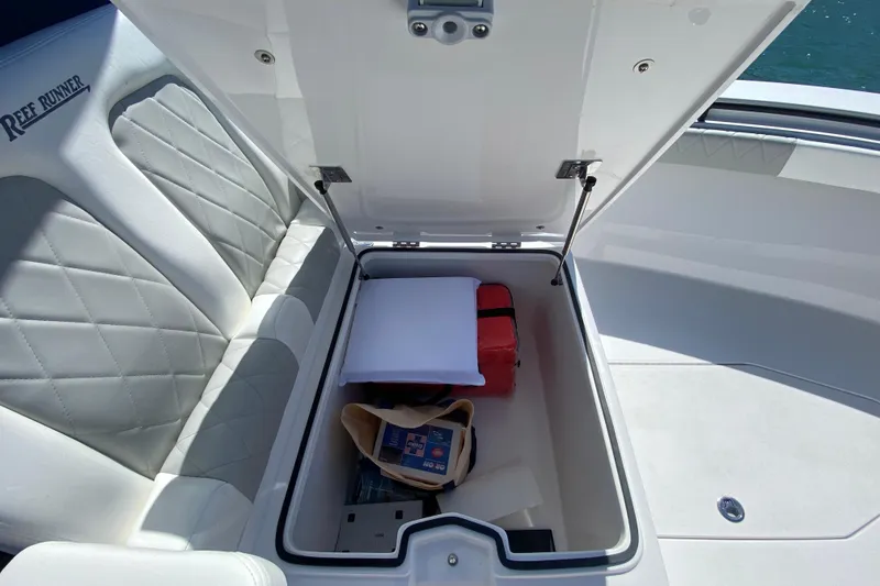 Slide: The Image of Open storage compartment on 2026 Reef Runner 280 boat with cushioned seating. - 21