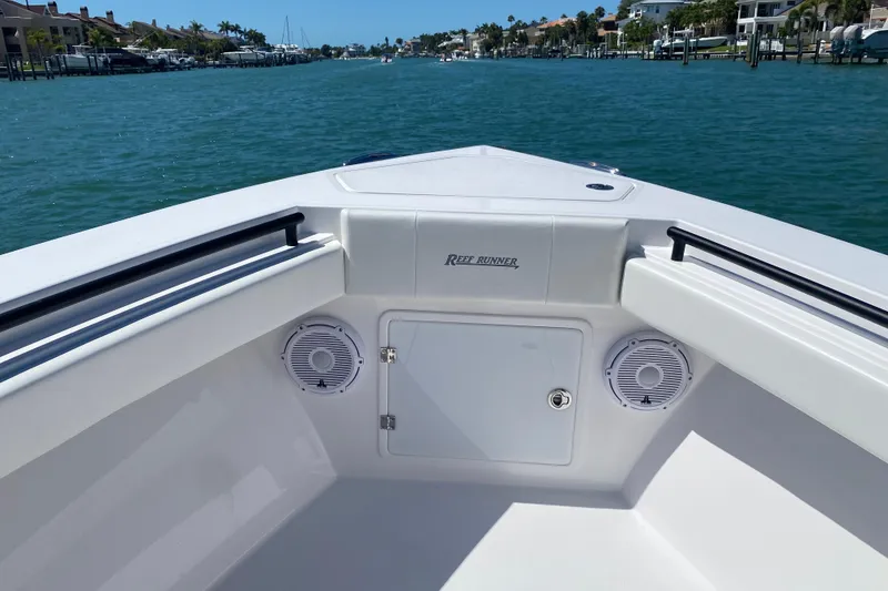 Slide: The Image of 2026 Reef Runner 280 boat bow with speakers, cruising on a sunny waterway. - 22