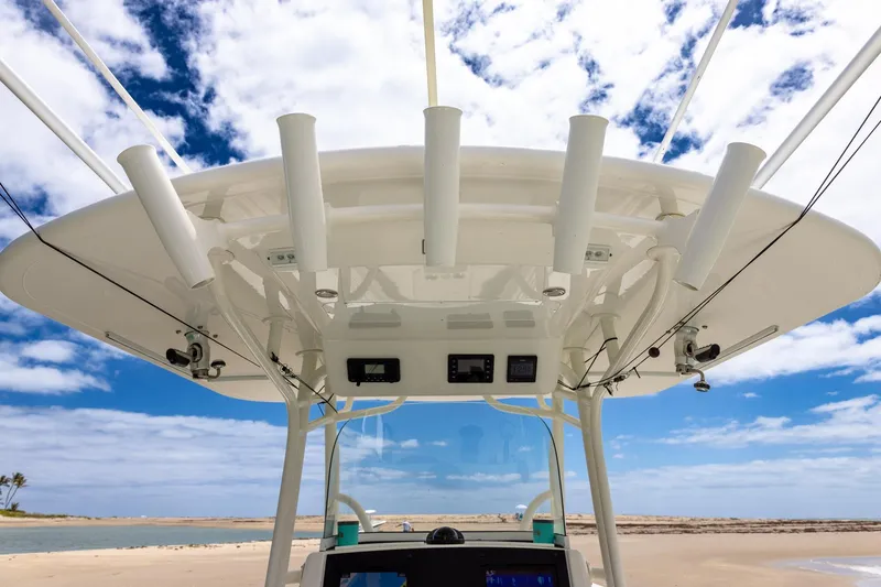 Slide: The Image of 2018 Regulator 28 boat with rod holders, clear sky, and sandy beach background. - 16