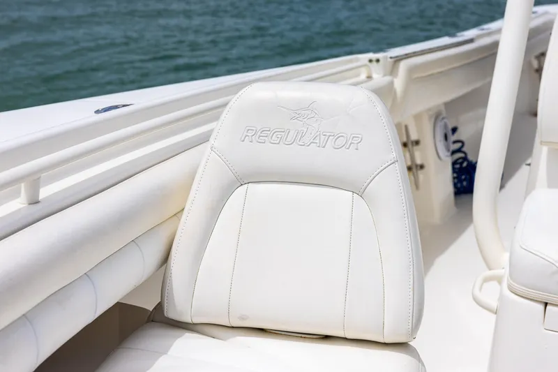 Slide: The Image of 2018 Regulator 28 boat seat with logo, featuring white upholstery and ocean backdrop. - 26