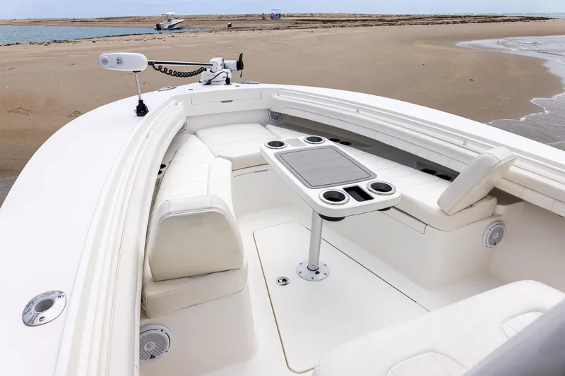 Slide: The Image of 2018 Regulator 28 boat interior with seating and table, docked on sandy beach. - 27