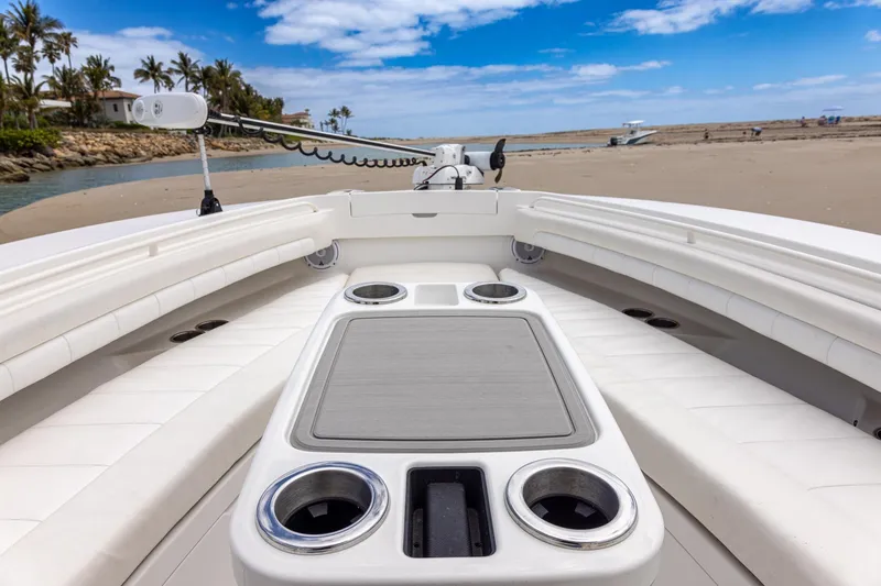 Slide: The Image of 2018 Regulator 28 boat interior with cup holders, sandy beach, and blue sky background. - 28