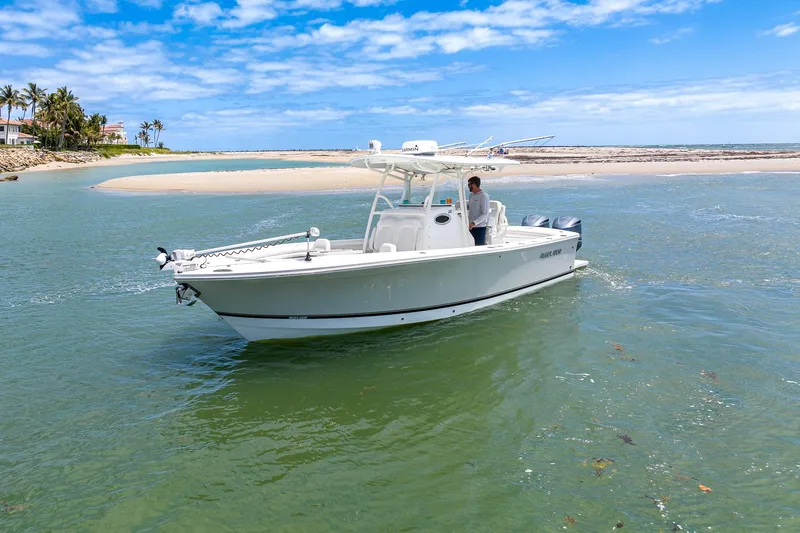 Slide: The Image of 2018 Regulator 28 boat cruising near a sandy shoreline under a clear blue sky. - 31