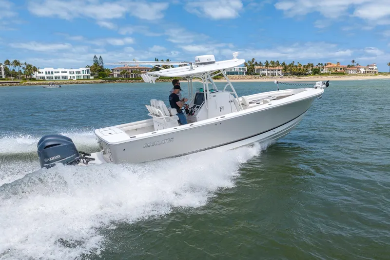 Slide: The Image of 2018 Regulator 28 boat cruising on water with Yamaha engine, coastal homes in background. - 32