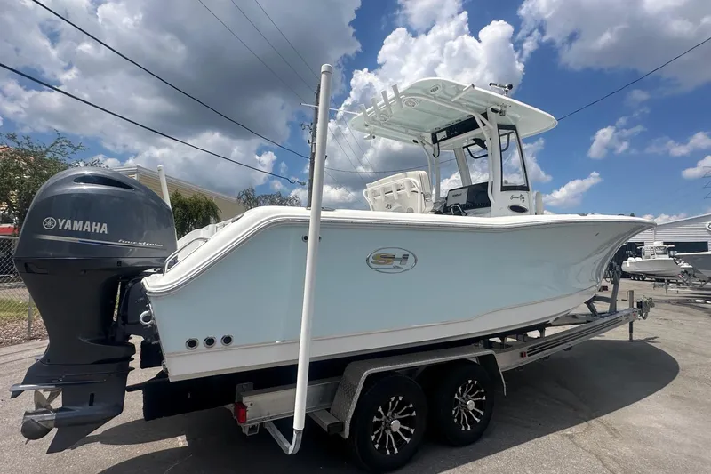 Slide: The Image of 2019 Sea Hunt Gamefish 27 Coffin Box boat on trailer, Yamaha engine, under cloudy sky. - 2