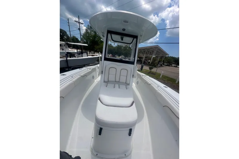 Slide: The Image of 2019 Sea Hunt Gamefish 27 Coffin Box boat interior with seating and console under a cloudy sky. - 4