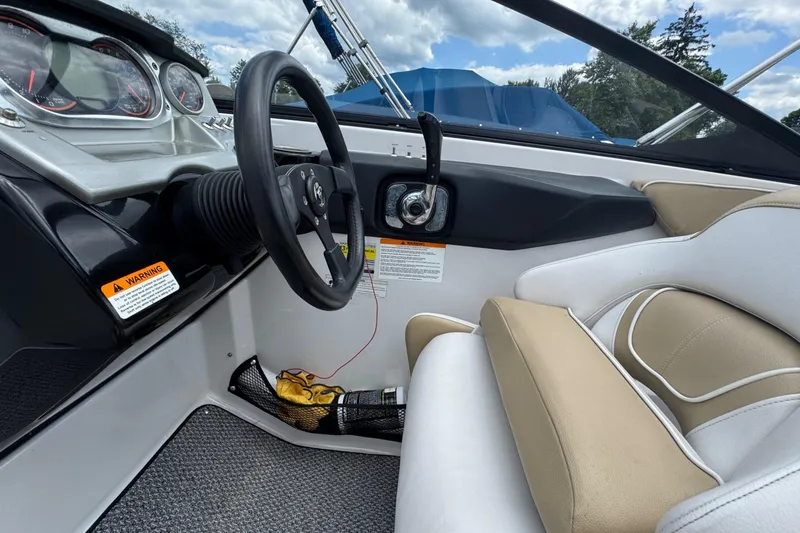 Slide: The Image of Interior of a 2015 Scarab 255 Platinum boat, featuring steering wheel and beige seating. - 9