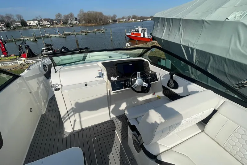Slide: The Image of 2019 Sea Ray SDX 250 boat interior with steering wheel and seating, docked by a lake. - 12