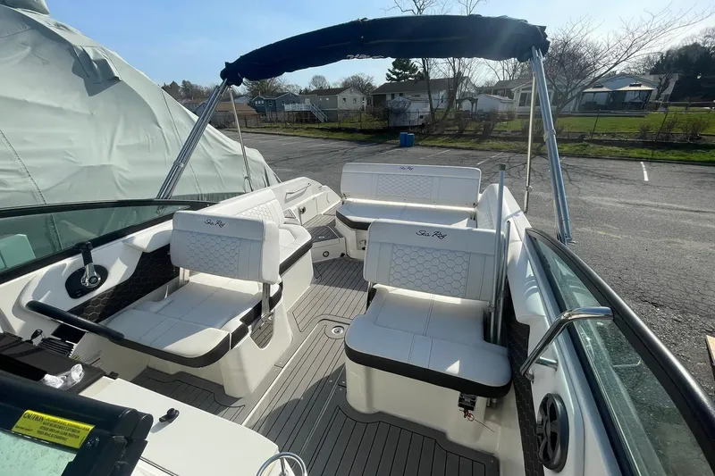 Slide: The Image of 2019 Sea Ray SDX 250 boat interior with white seating and canopy in a parking area. - 13