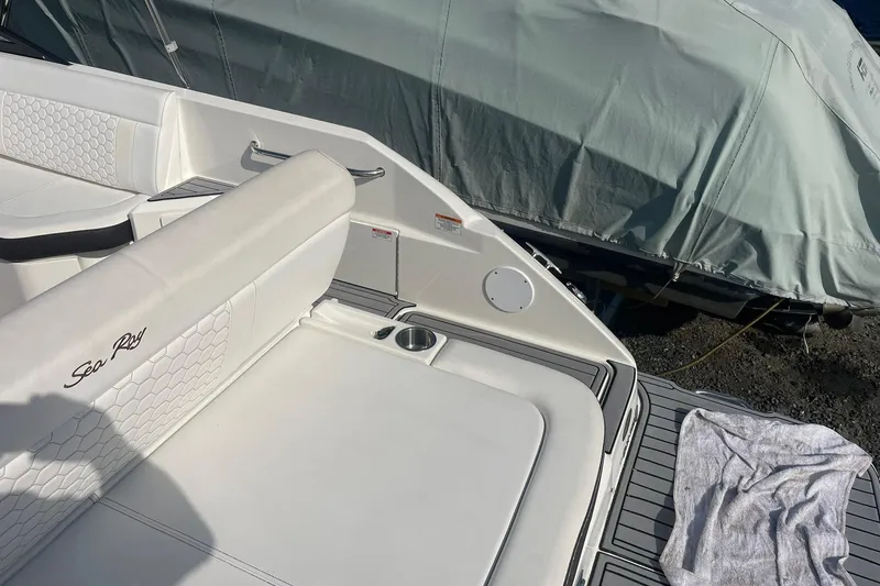 Slide: The Image of 2019 Sea Ray SDX 250 boat interior with white seating and covered vessel nearby. - 15