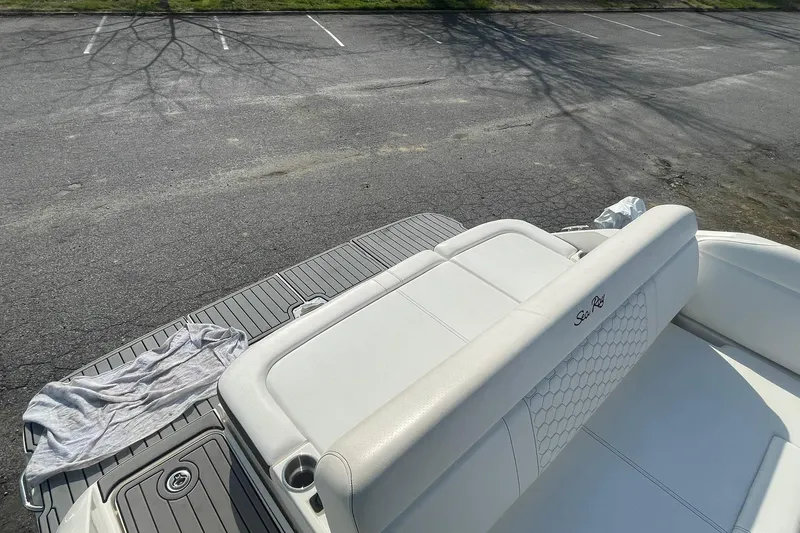 Slide: The Image of 2019 Sea Ray SDX 250 boat with white seating and gray deck, parked on asphalt. - 18