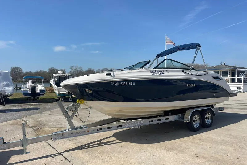 Slide: The Image of 2019 Sea Ray SDX 250 boat on trailer, parked outdoors under clear blue sky. - 2