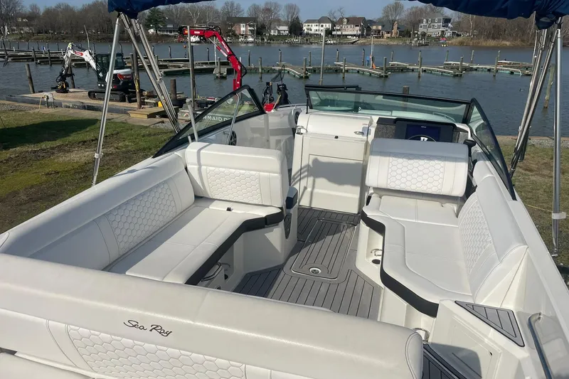 Slide: The Image of 2019 Sea Ray SDX 250 boat interior with white seating, docked by a scenic waterfront. - 8
