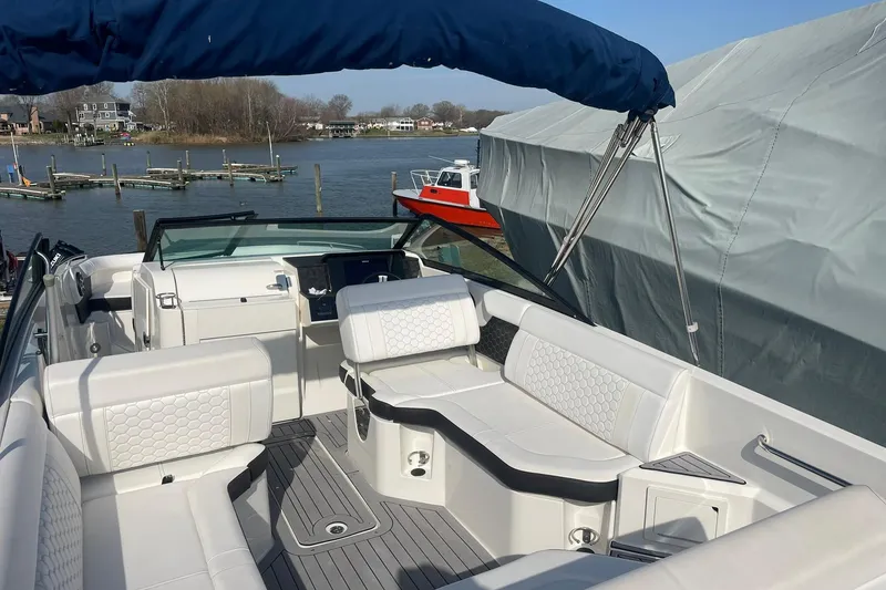 Slide: The Image of 2019 Sea Ray SDX 250 boat interior with white seating, docked by a scenic waterfront. - 9
