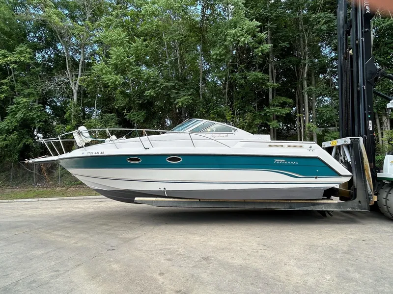 Slide: The Image of 1995 Chaparral Signature 310 boat on forklift, surrounded by trees. - 4