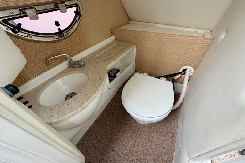 Slide: The Image of 2014 Cobalt 24SD WSS boat bathroom with sink, toilet, and porthole window. - 16