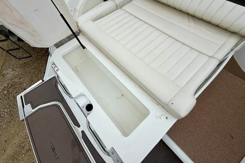 Slide: The Image of 2014 Cobalt 24SD WSS boat interior with white seating and storage compartment. - 5