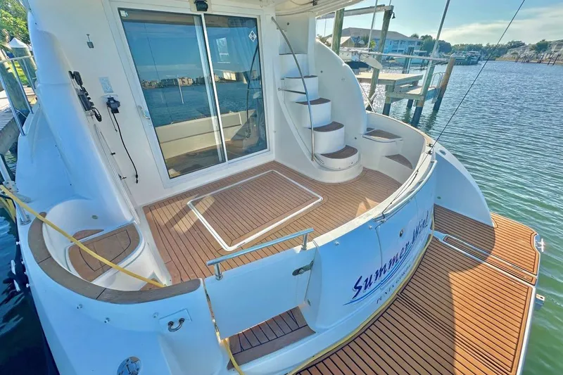 Slide: The Image of 2007 Meridan 391 yacht deck with wooden flooring and spiral staircase by the water. - 5