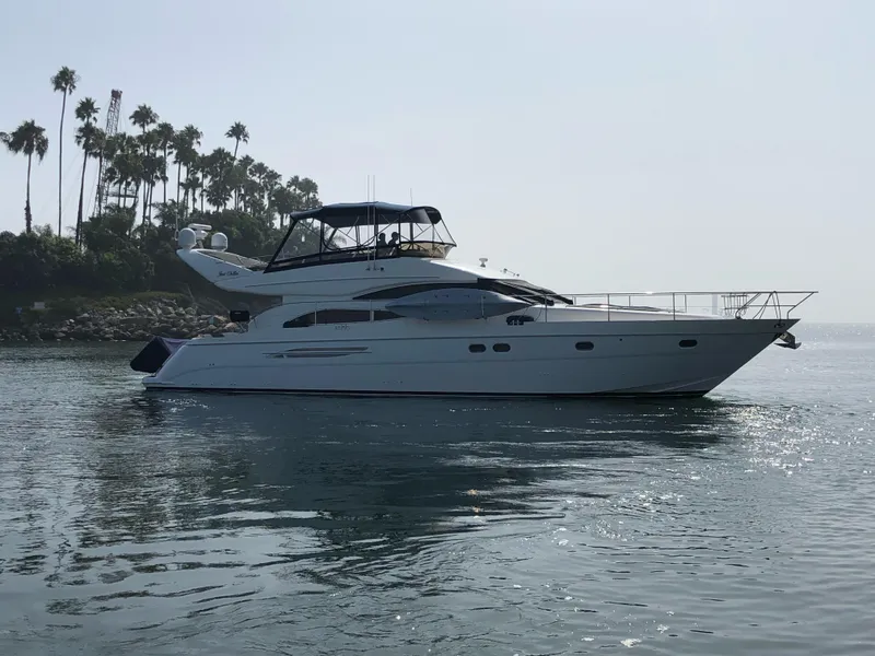 Slide: The Image of 2006 Viking Princess 61 Flybridge yacht on calm water near palm trees. - 2