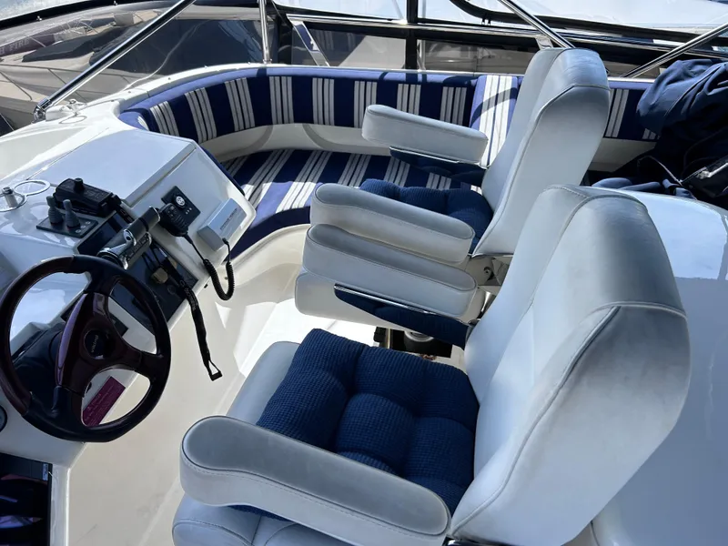 Slide: The Image of 2006 Viking Princess 61 Flybridge helm with striped seating and steering wheel. - 34
