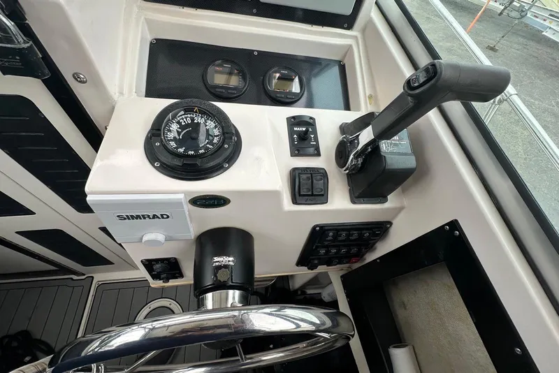 Slide: The Image of 1997 Grady-White Seafarer 228 boat dashboard with compass, controls, and Simrad equipment. - 25