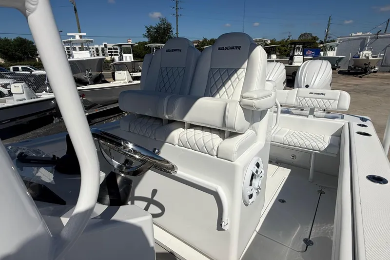 Slide: The Image of 2025 Bluewater 25t boat interior with white cushioned seating and steering wheel. - 12