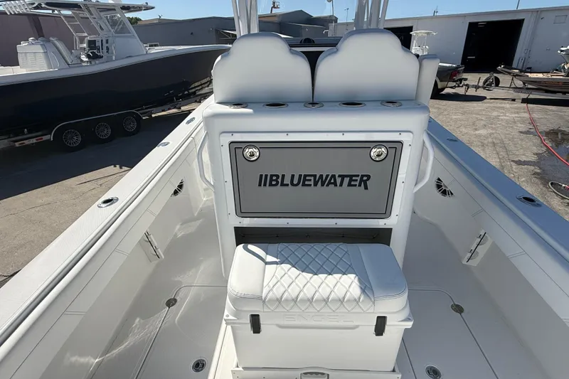 Slide: The Image of 2025 Bluewater 25t boat interior with seating and storage, docked outdoors. - 8