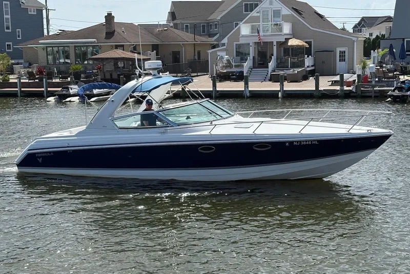 The Image of 2004 Formula 330 Sun Sport boat cruising on a sunny waterfront near houses. - 0