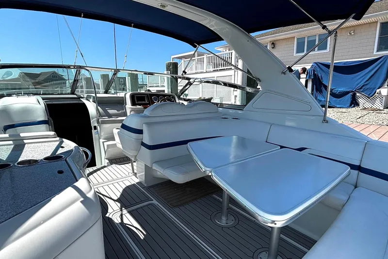 Slide: The Image of 2004 Formula 330 Sun Sport boat interior with seating and table under blue canopy. - 13