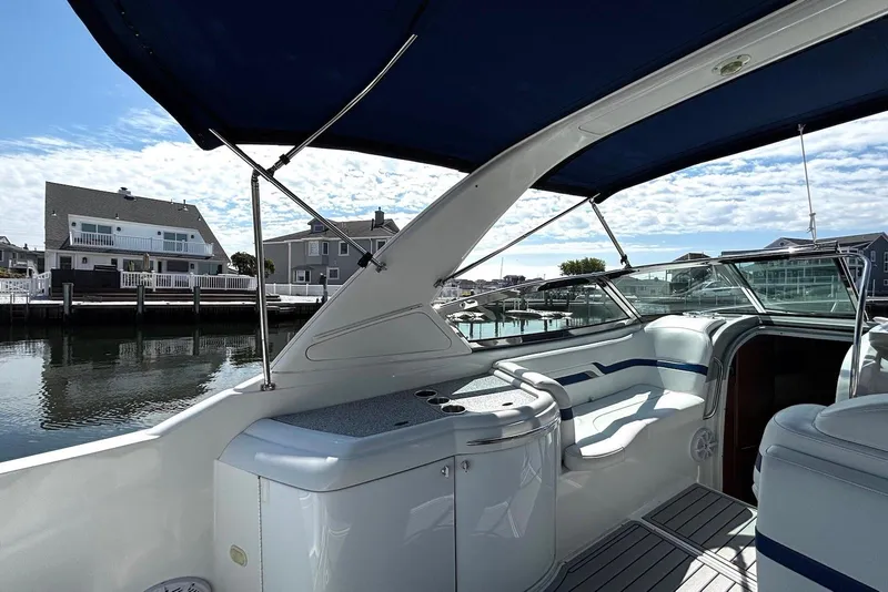 Slide: The Image of 2004 Formula 330 Sun Sport boat interior with blue canopy, docked near waterfront homes. - 14