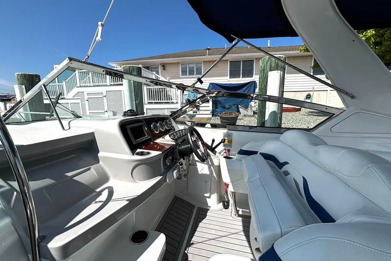 Slide: The Image of 2004 Formula 330 Sun Sport boat interior with steering wheel and seating, docked near a house. - 15