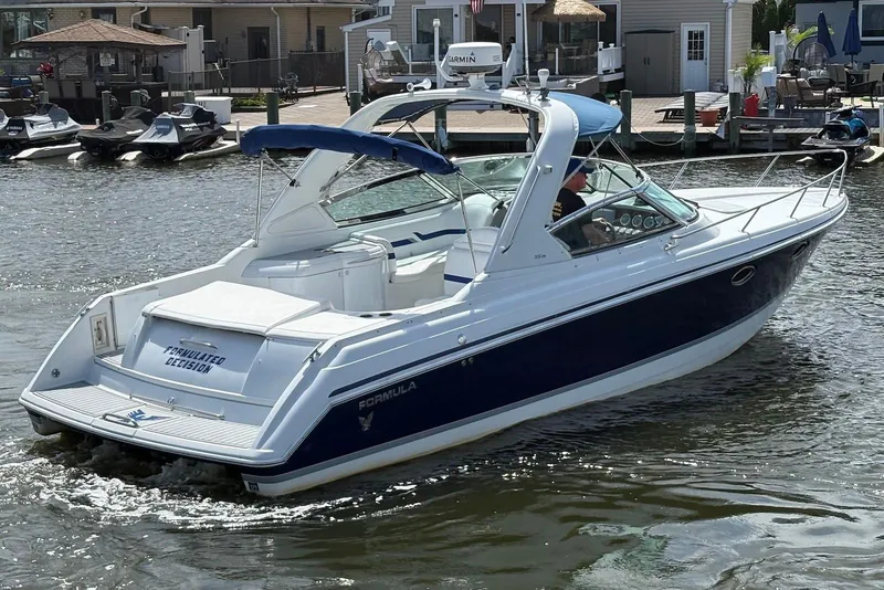 Slide: The Image of 2004 Formula 330 Sun Sport boat cruising on a sunny day near docks. - 2