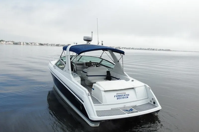 Slide: The Image of 2004 Formula 330 Sun Sport boat on calm water with blue canopy. - 7