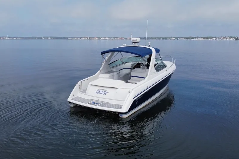 Slide: The Image of 2004 Formula 330 Sun Sport boat on calm water, featuring sleek design and blue canopy. - 8
