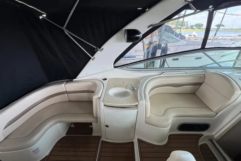 Slide: The Image of 2006 Chaparral 330 Signature boat interior with seating and sink, docked by the water. - 17