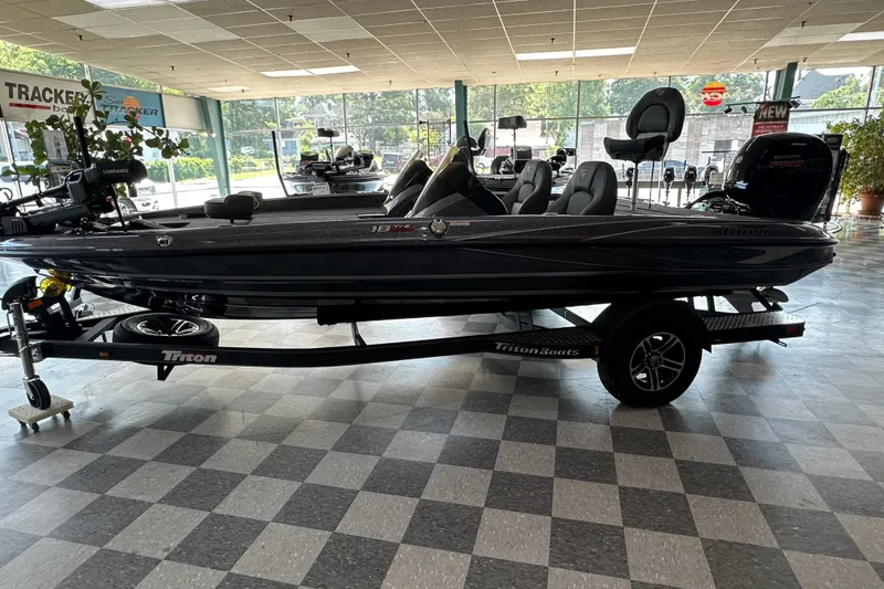 Slide: The Image of 2024 Triton 18 TrX bass boat displayed indoors on a trailer. - 2
