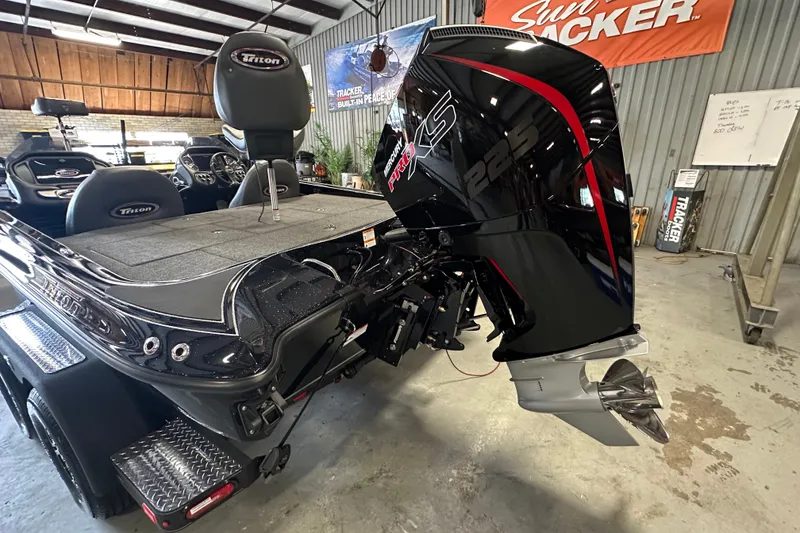 Slide: The Image of 2025 Triton 19 TrX Patriot boat with powerful outboard motor in a garage setting. - 13