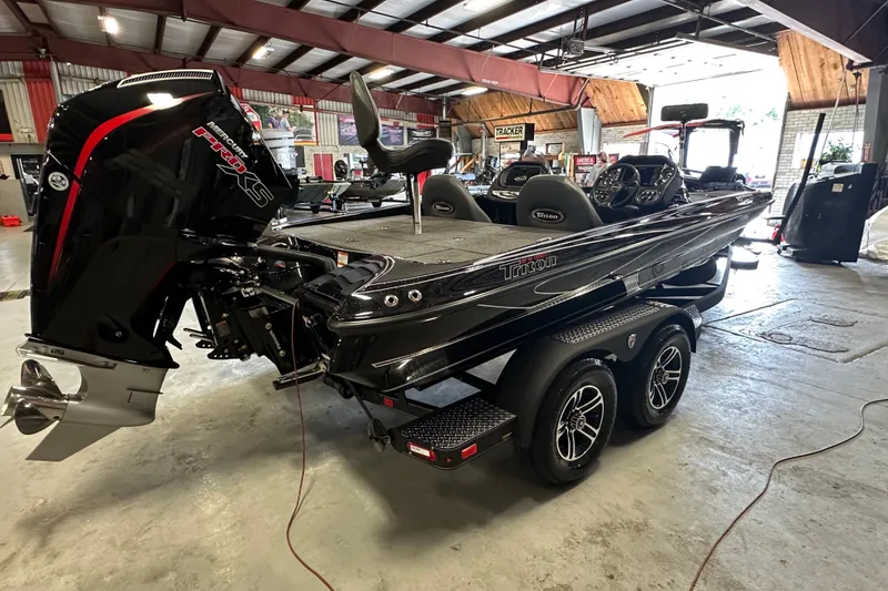 Slide: The Image of 2025 Triton 19 TrX Patriot boat in a garage, featuring a powerful engine and sleek design. - 5