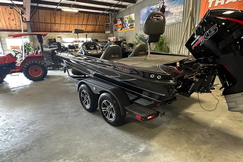 Slide: The Image of 2025 Triton 19 TrX Patriot bass boat in a showroom with a Mercury Pro XS engine. - 7