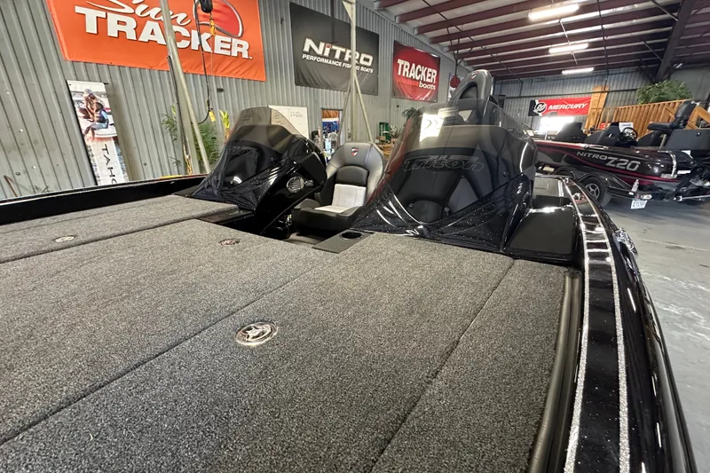 Slide: The Image of 2025 Triton 19 TrX Patriot boat in showroom, featuring sleek design and spacious deck. - 10