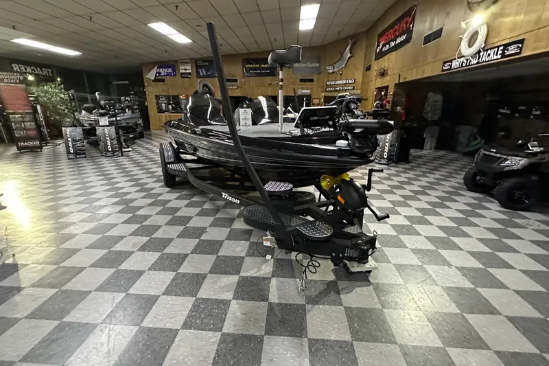 Slide: The Image of 2025 Triton 19 TrX Patriot boat displayed in showroom with checkered flooring. - 75