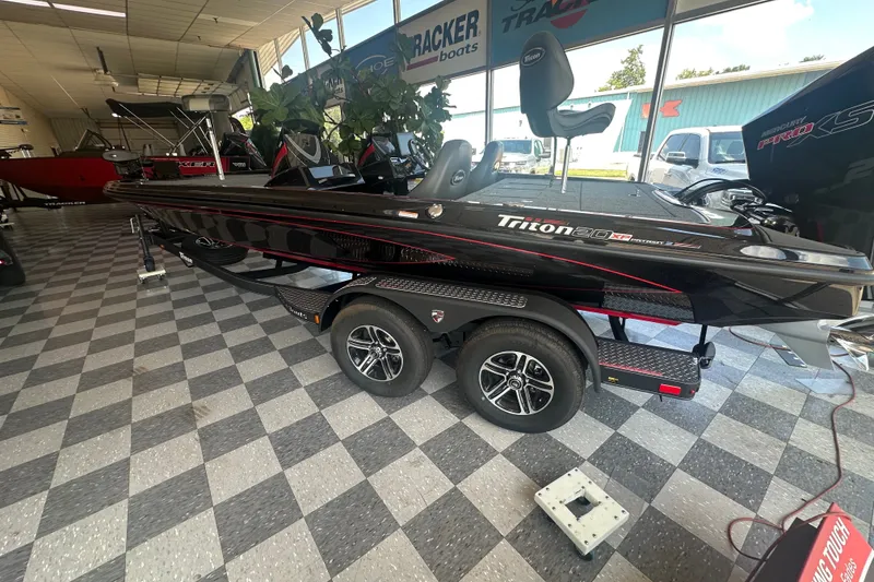 Slide: The Image of 2026 Triton 20XP Patriot boat displayed in showroom with checkered flooring. - 129