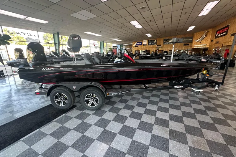 The Image of 2026 Triton 20XP Patriot boat displayed in showroom, featuring sleek black design and dual-axle trailer. - 0